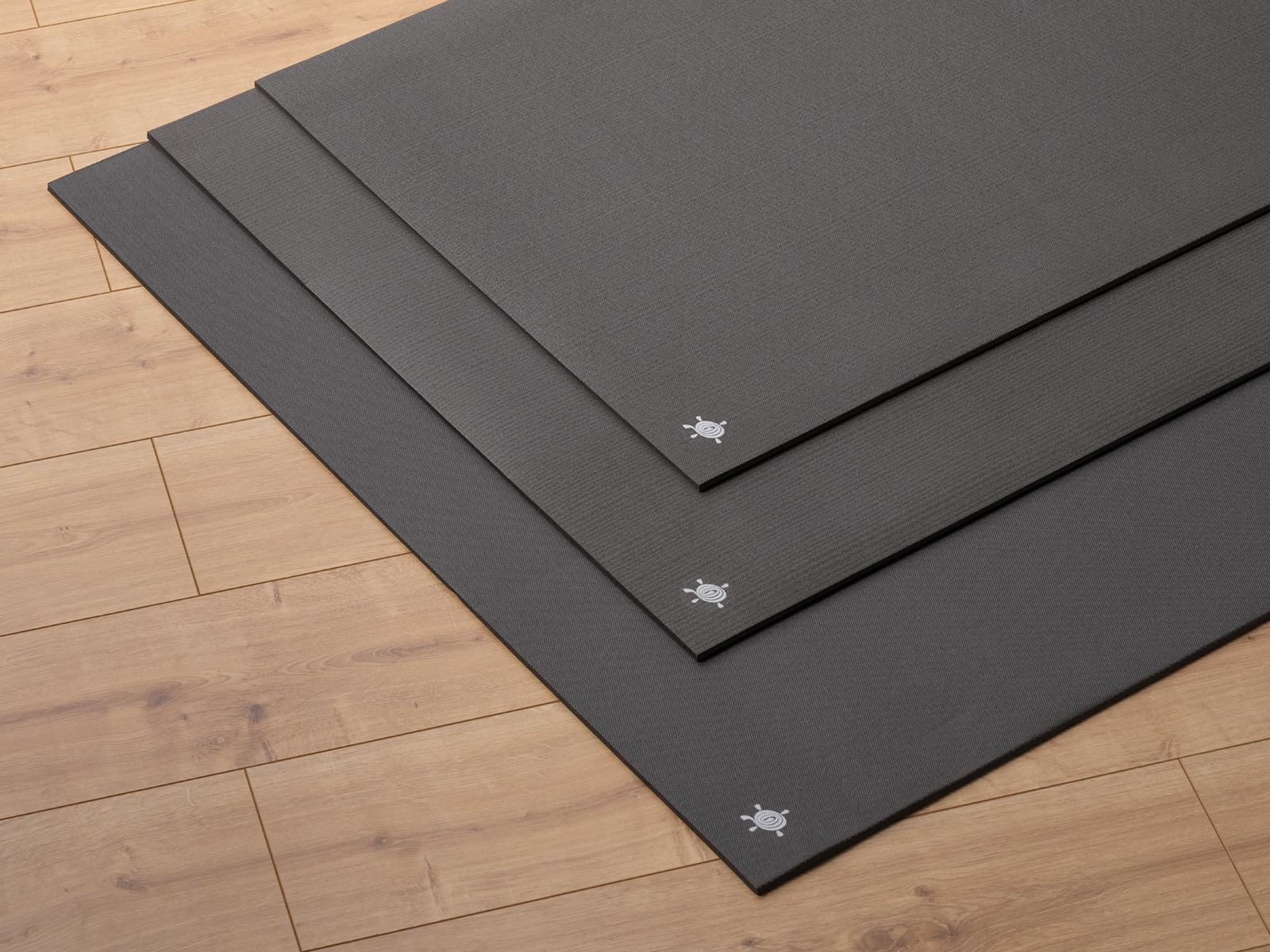 Kurma CORE Black Yogamatten in 3 Größen auf Parkettboden gestapelt